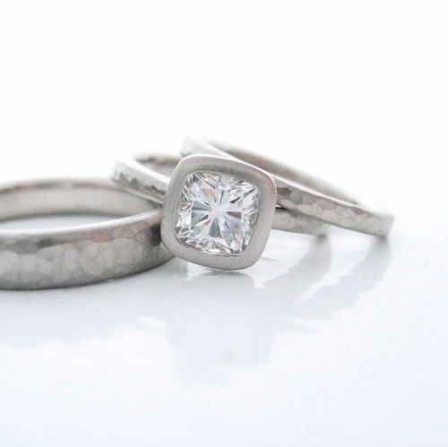softly hammered wedding bands with cushion cut diamond solitaire in a bezel setting