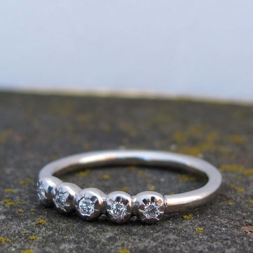 Platinum ring with five diamonds on a textured surface