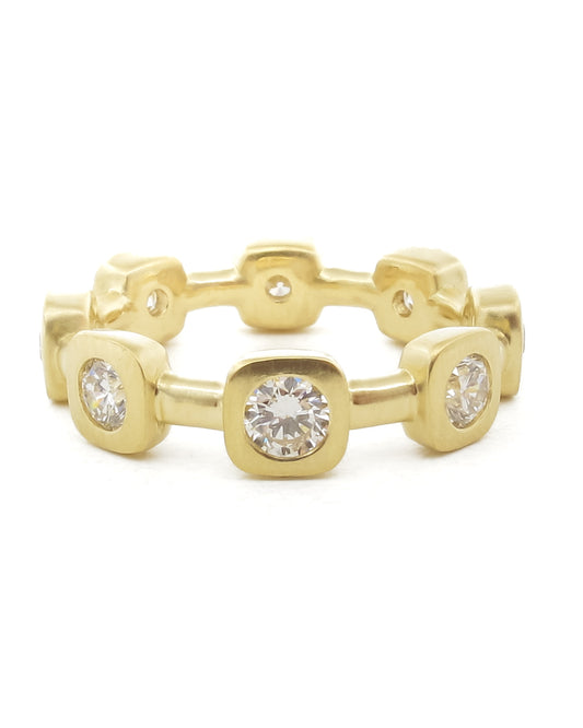 Yellow gold diamond eternity band featuring round brilliant diamonds set in square bezel settings. The matte finished ring has alternating larger and smaller diamond stations with a geometric, modern design. Each diamond is flush-set within square gold frames, creating a contemporary wedding or anniversary band.​​​​​​​​​​​​​​​​