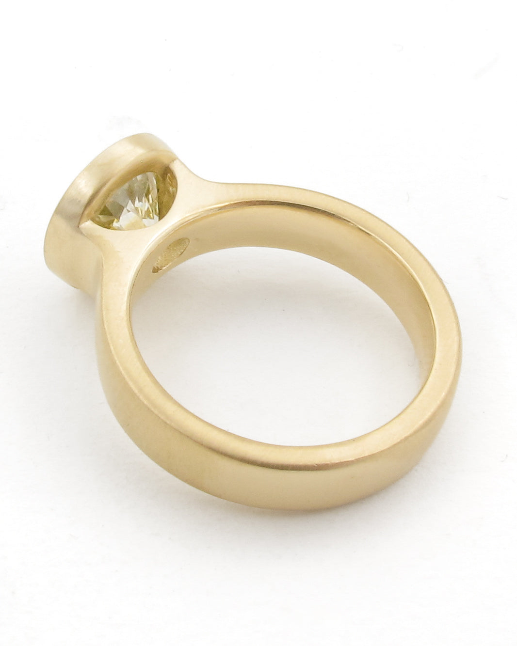A yellow gold ring with a single large diamond in a open bezel setting, shown on a plain white background.
