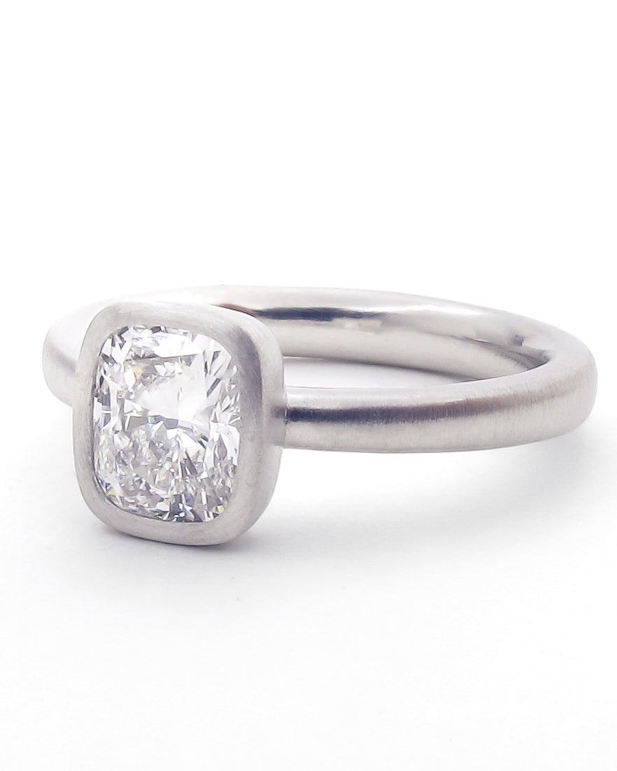 Three quarter view of cushion cut diamond bezel ring