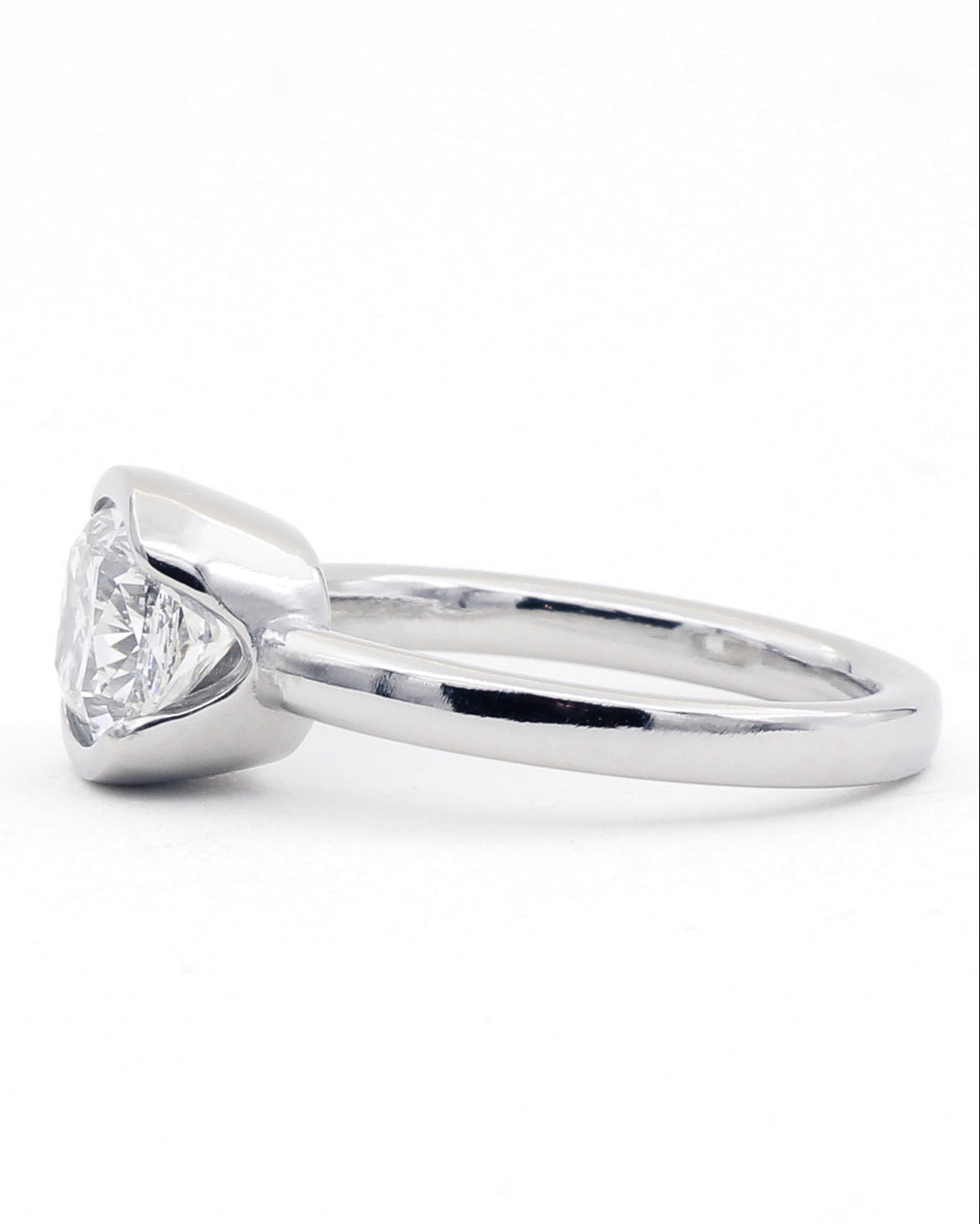 Platinum diamond ring with a narrow band and a split bezel, view from the side.