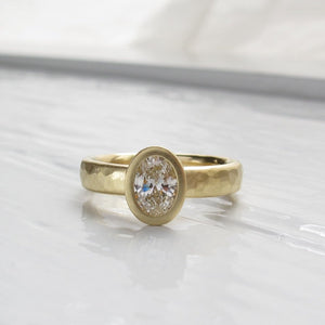 Oval diamond bezel set engagement ring with rustic hammered texture